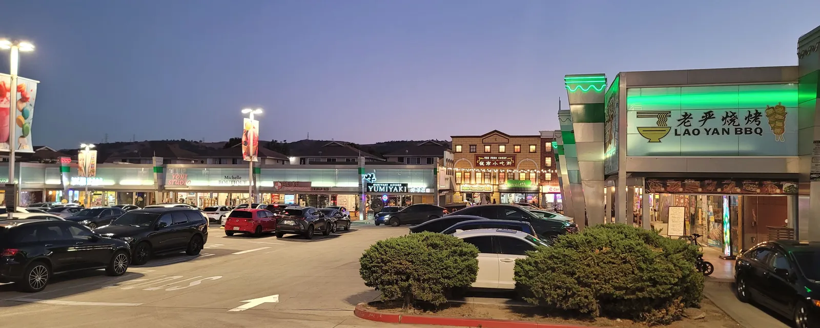 A plaza of restaurants and shops in Rowland Heights at dusk, with a barbecue restaurant sign
